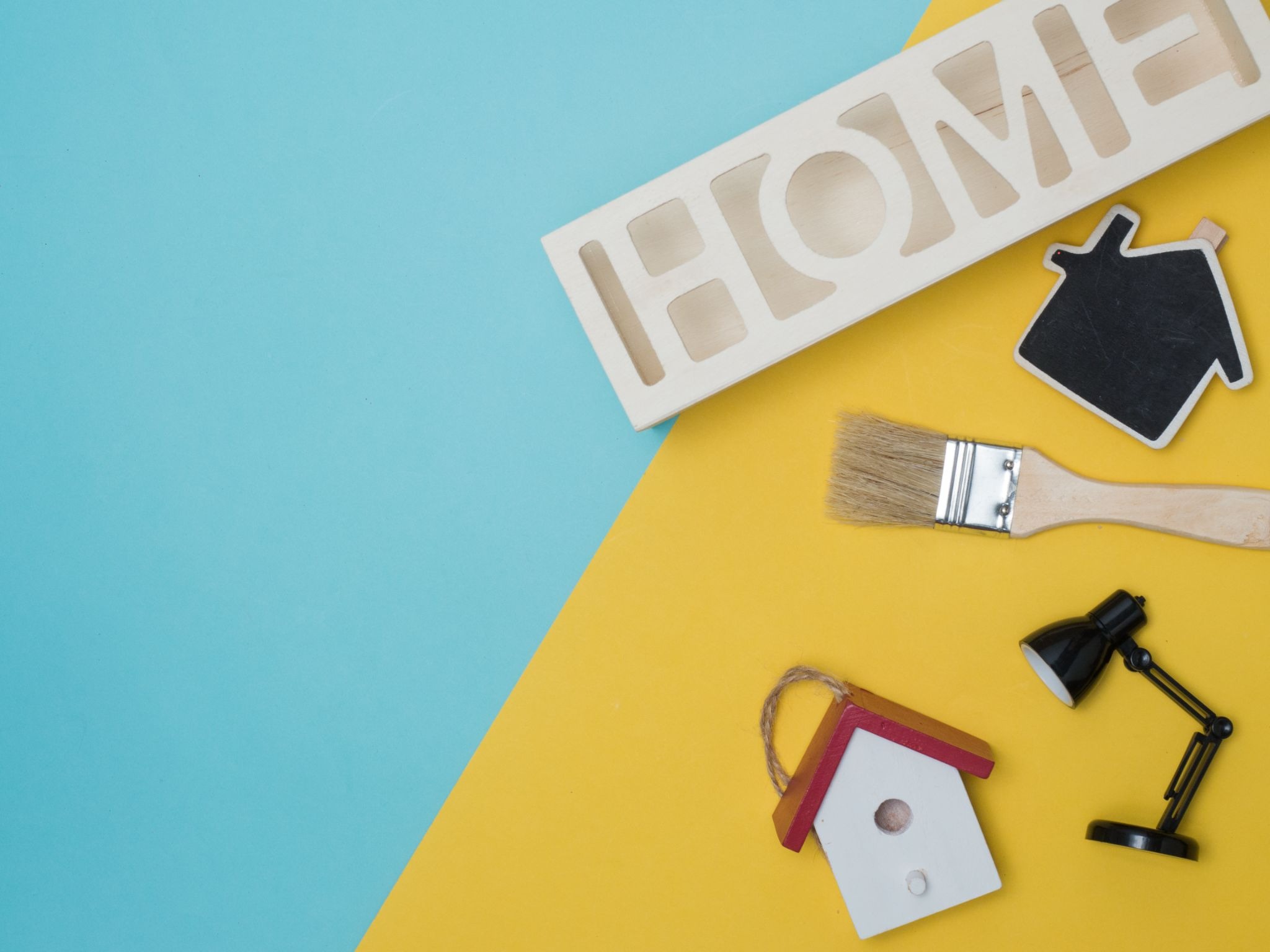 A home improvement concept with the word “Home” above a paintbrush, light, and the silhouette of a house.