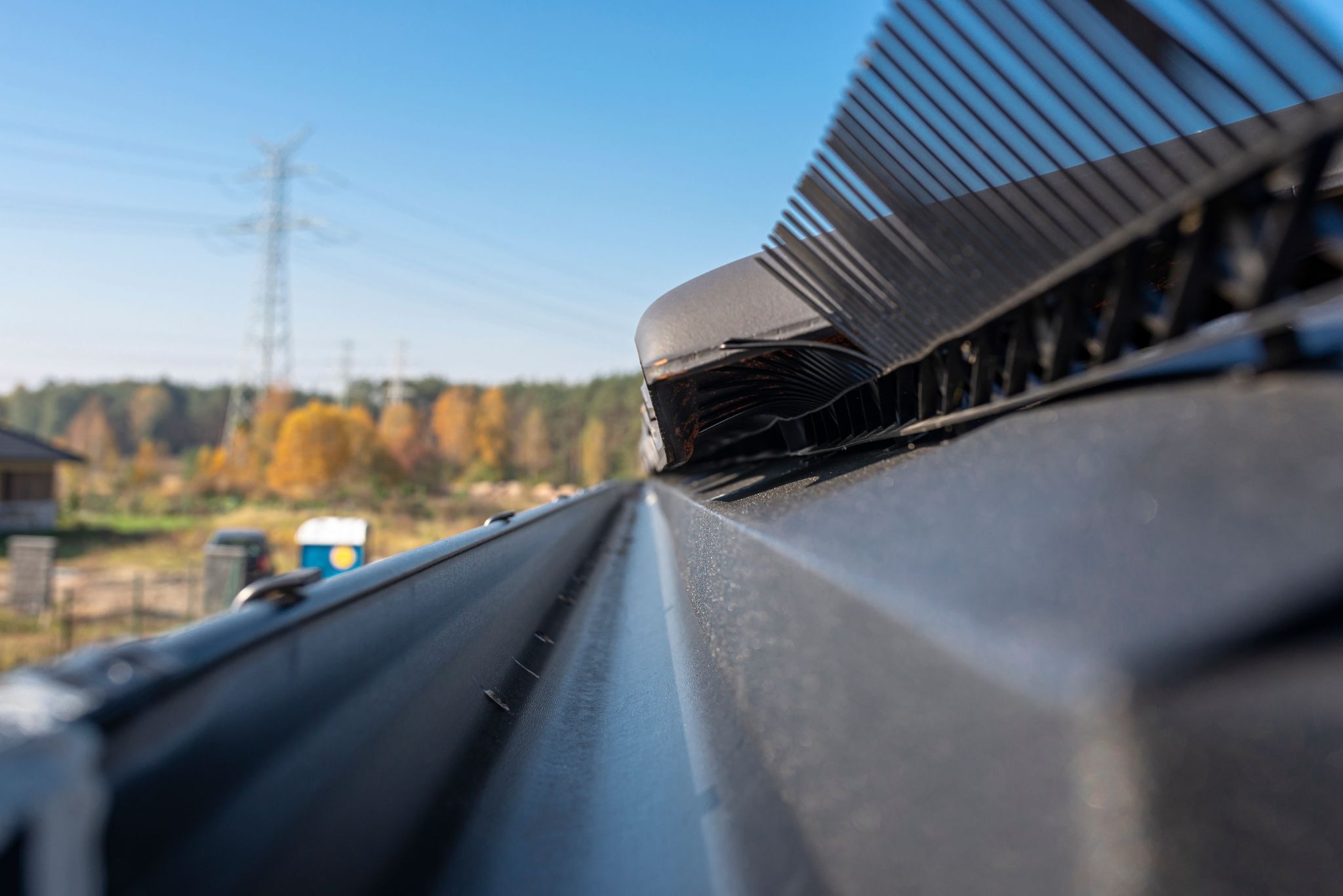 Detailed view of a black metal gutter system mounted below ceramic roof tiles