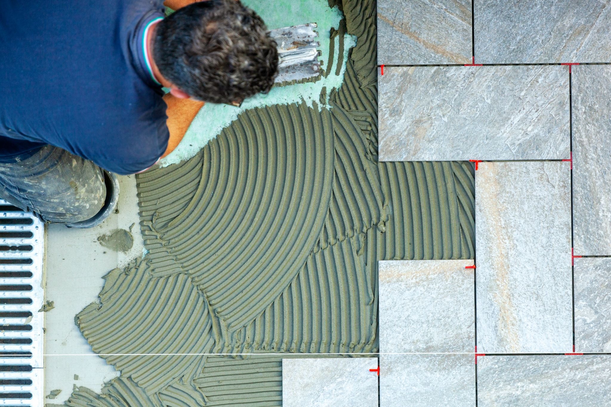 An aerial view of a worker laying tile flooring.