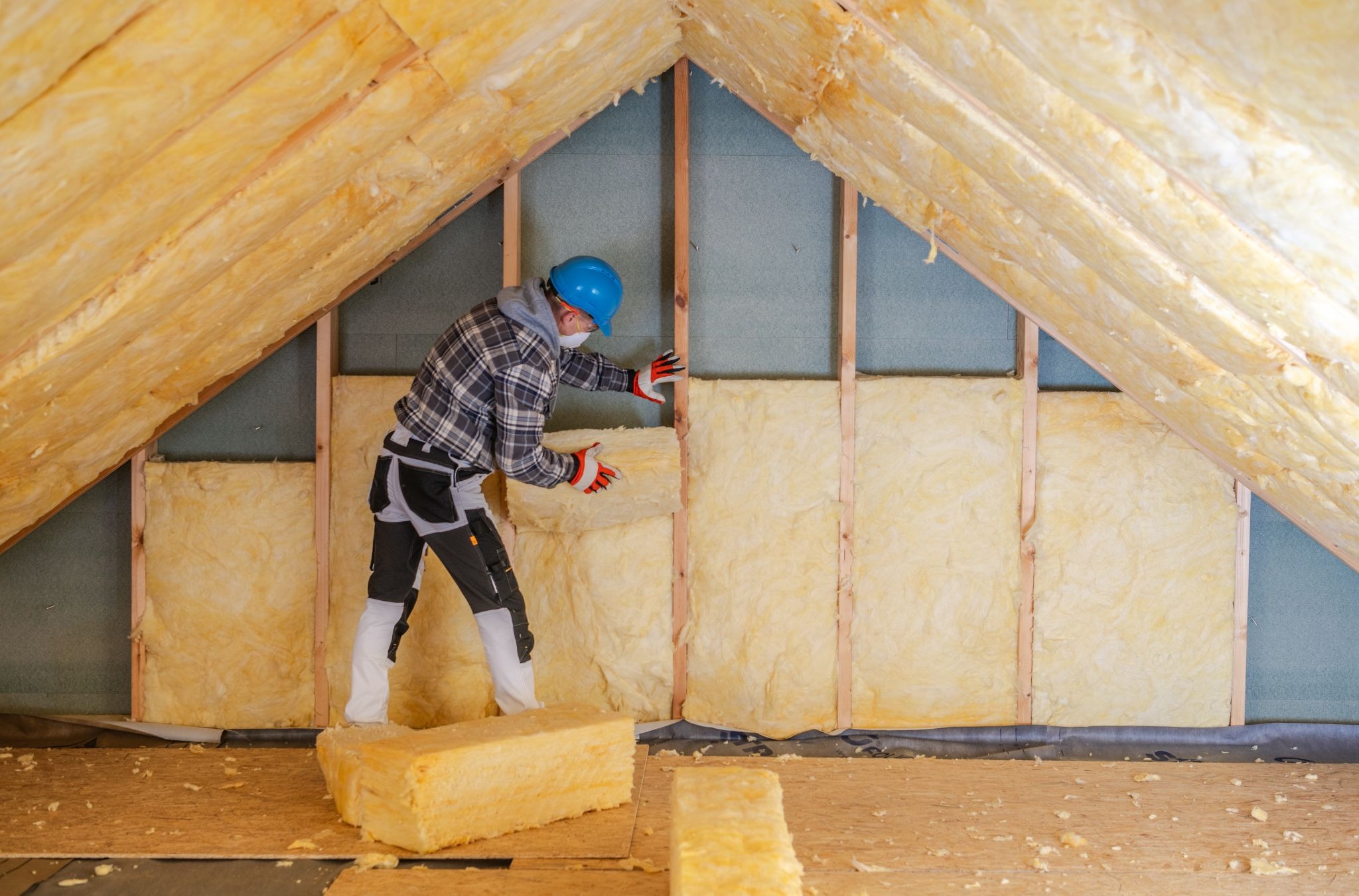 Professional insulation service worker installing attic insulation to improve home energy efficiency and indoor comfort