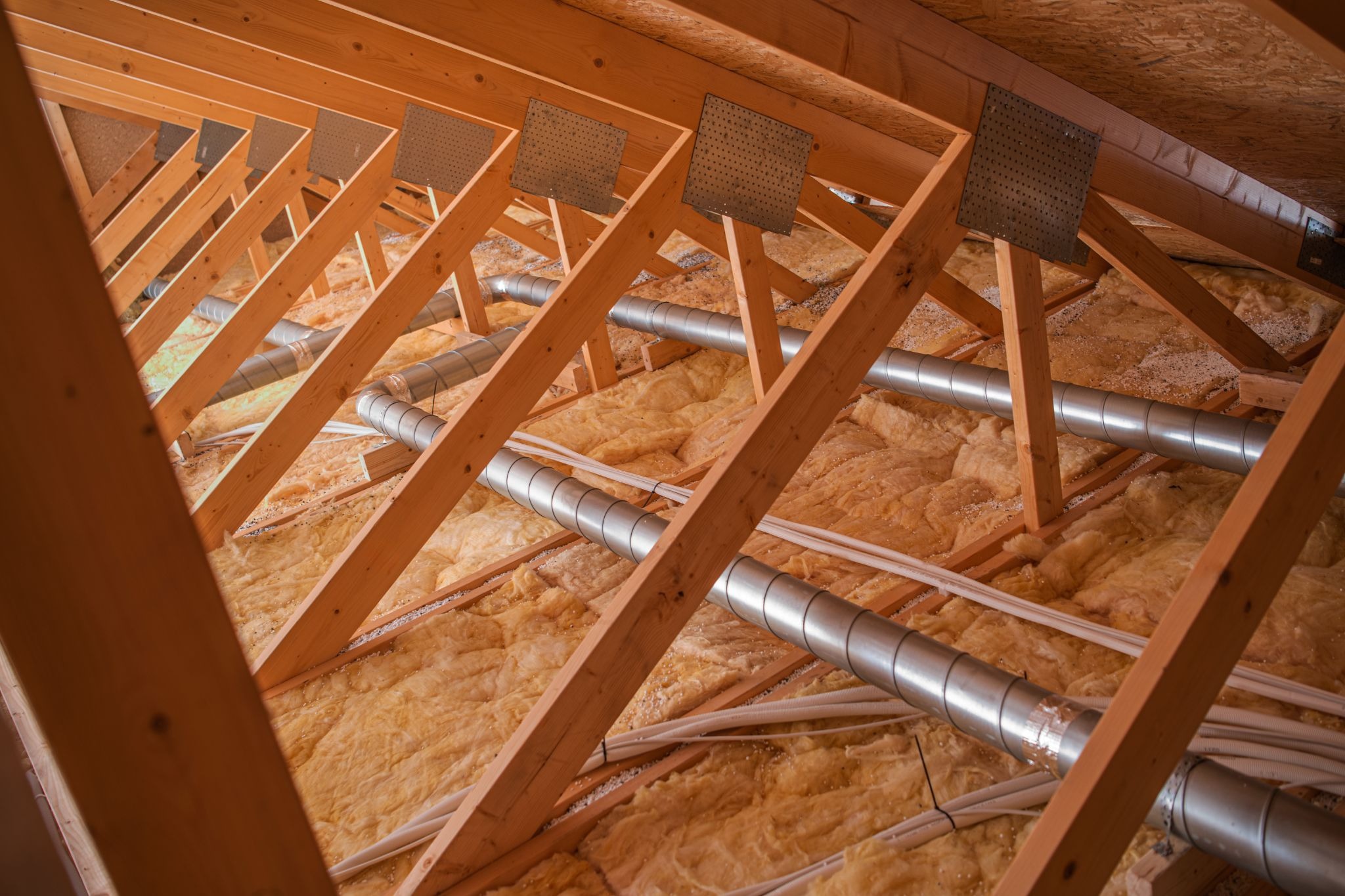 Attic view showing installed insulation baffles along rafters and ventilation pipes supporting proper airflow and temperature control