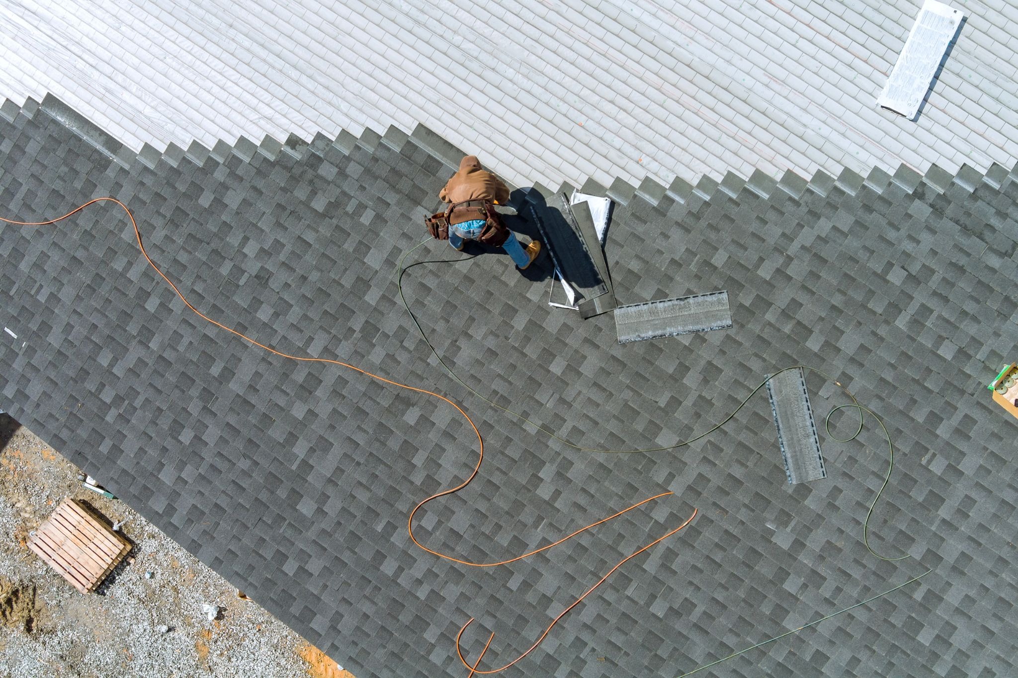 Overhead view of a worker installing new materials during a roof replacement project